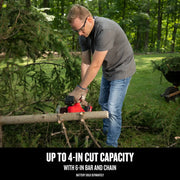 Photo of person using Craftsman CMCCS320B cordless chainsaw to cut a tree branch outdoors, branch debris visible.